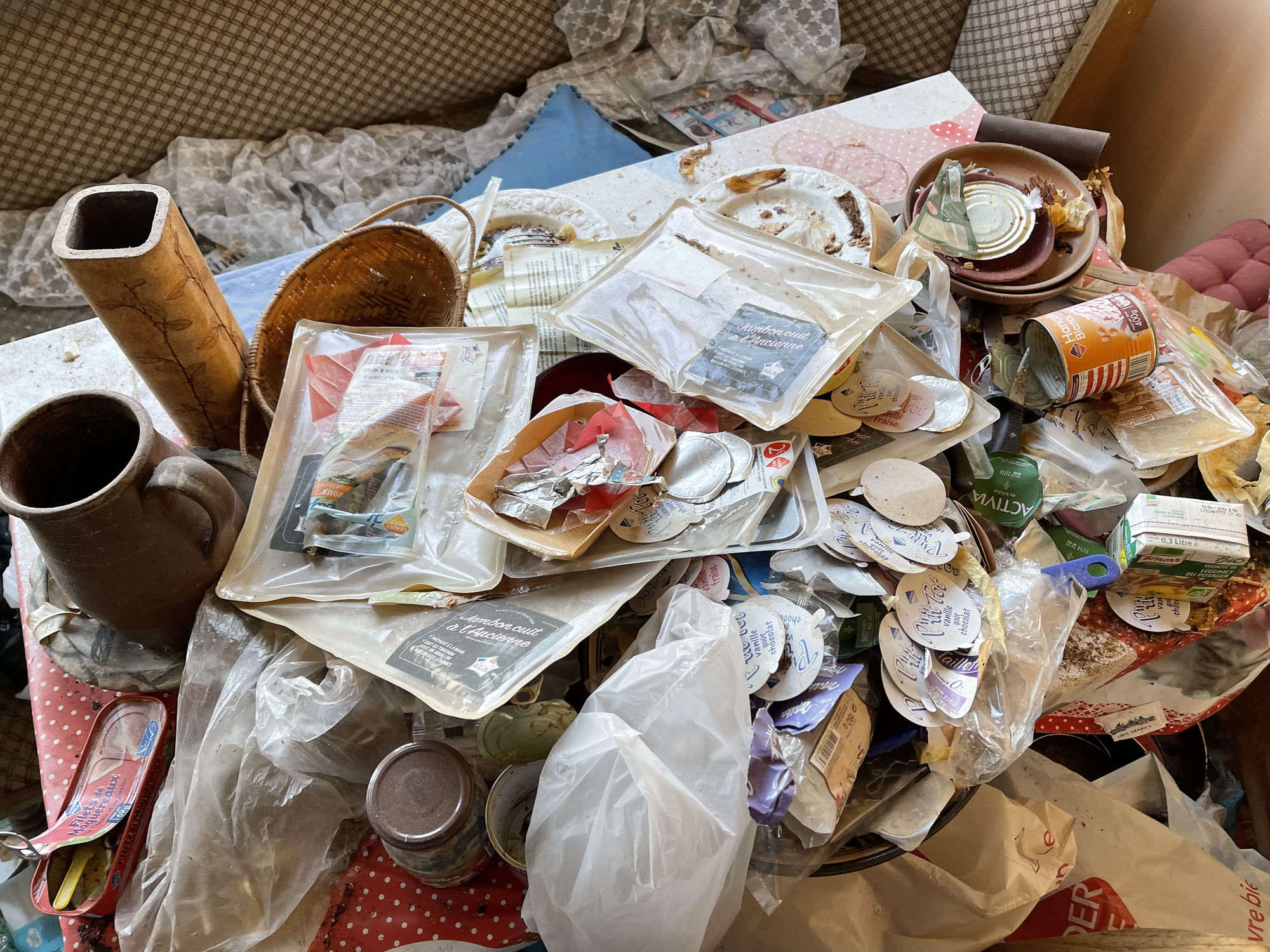 Détail rapproché : emballages alimentaires usagés, barquettes, papiers — exemple de syllogomanie